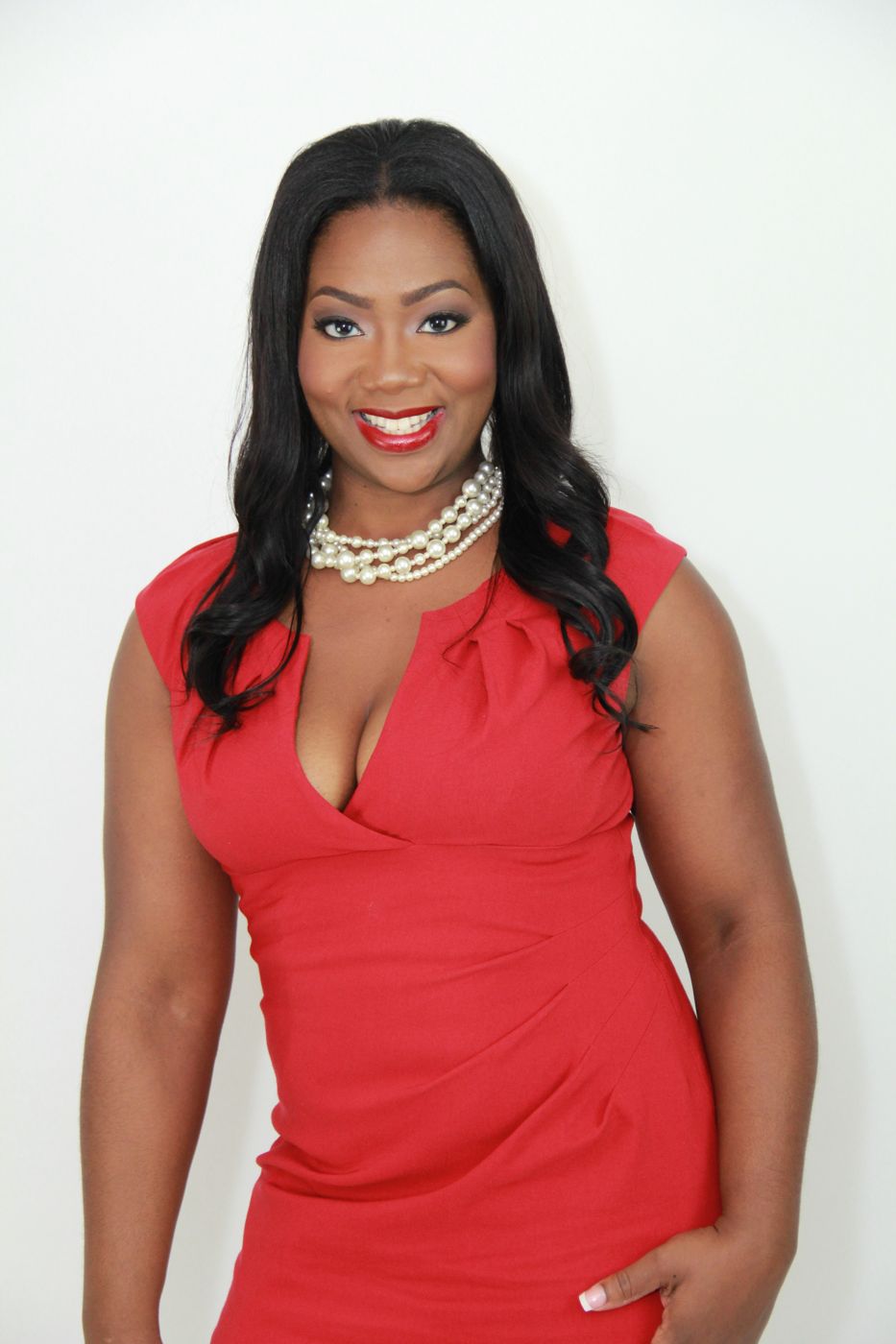 Jocelyn Dena’e smiling in a red dress and pearl necklace